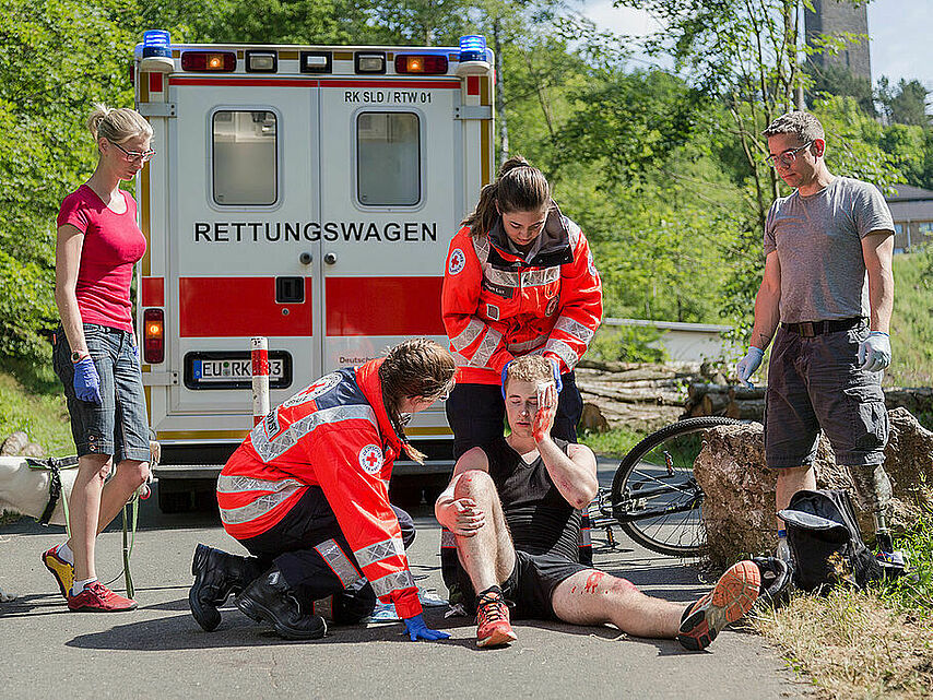Erste Hilfe beim Unfall mit dem Mountainbike: Rettungssanitäter bei der Versorgung des Unfallopfers